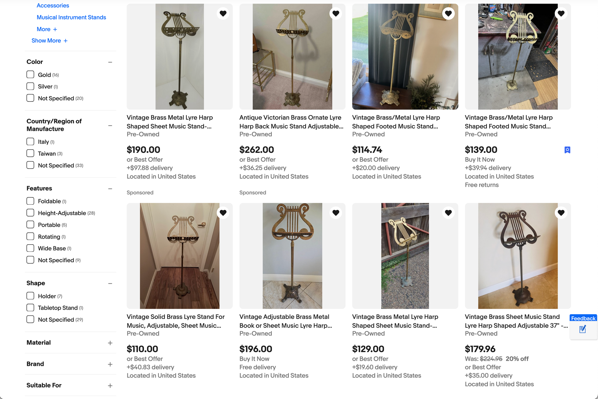 A screenshot of eBay search results showing eight brass lyre-shaped music stands ranging from $110 to $262